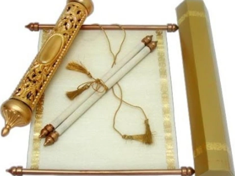 In a traditional Indian wedding setting, a gold and white scroll, adorned with a tassel is displayed